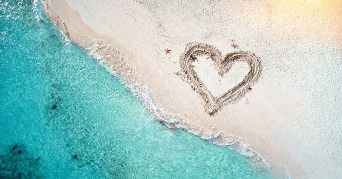 Heart drawn in sand on a tropical beach with starfish and turquoise water