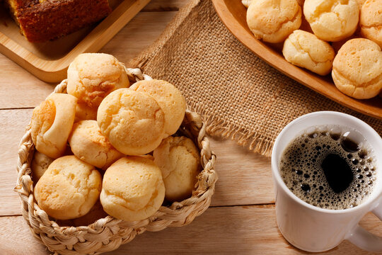 A cup of black coffee accompanied by homemade cheese bread, served in a natural fiber basket on a rustic wooden table.
