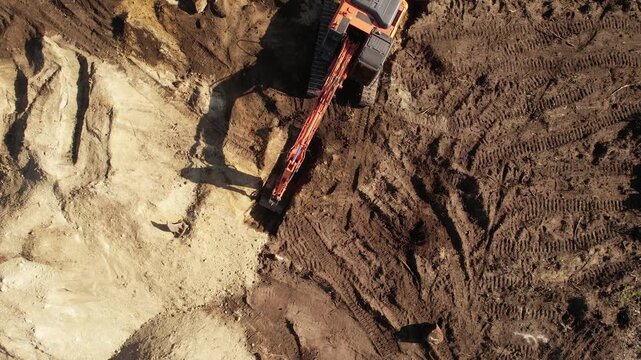Aerial view from above of an excavator operating at dawn.