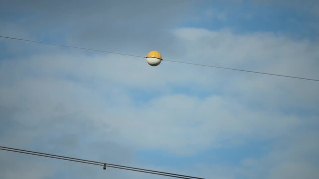 Aircraft warning sphere mounted on overhead utility infrastructure for aviation visibility.