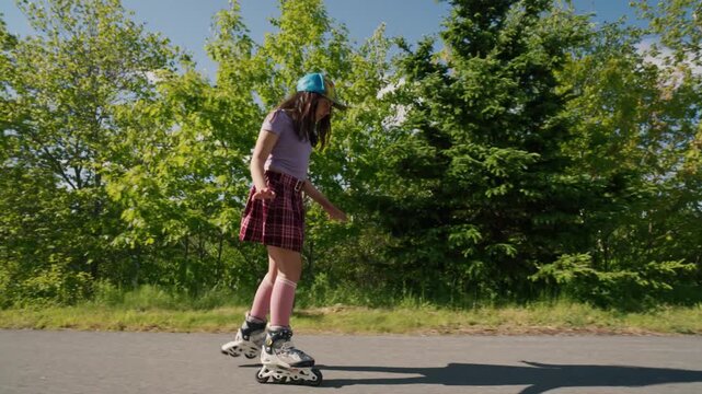 A girl in a cheerful outfit rolls gracefully on her skates along a sunny path. The lush trees create a beautiful backdrop for her playful adventure on a summer day.