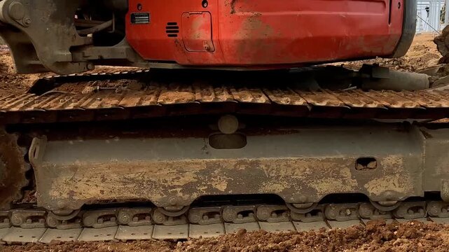 Close-up of excavator crawler track operating on a construction site, representing heavy equipment and earthmoving work.