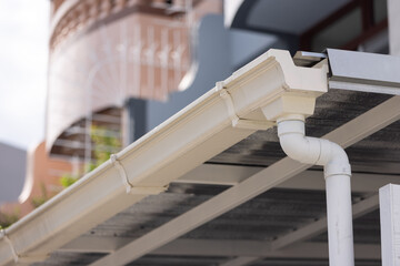 Gutter connected to downspout under solar panel roof © Rattanachat