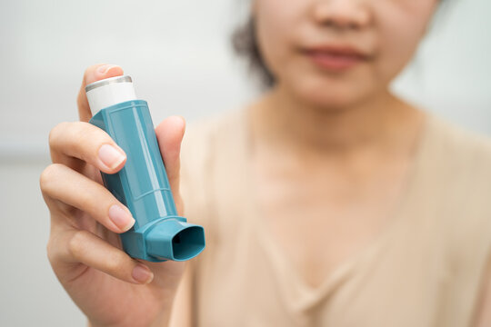 Asthma and chronic obstructive pulmonary disease COPD, Asian woman using metered dose inhaler MDI.