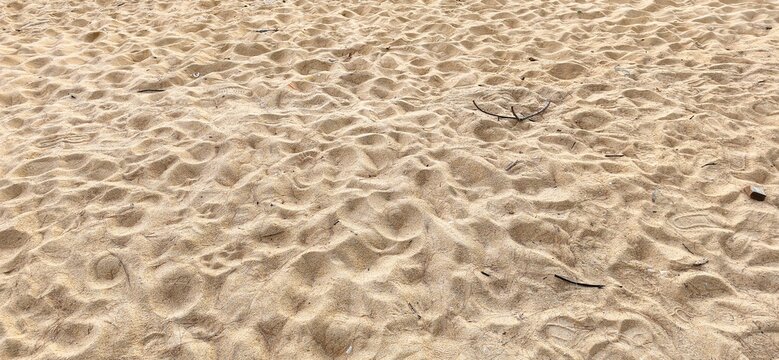 Detailed texture of sand dunes on a beach created by wind and footsteps.