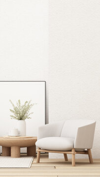 Minimalist Nordic lounge with a white armchair, oak coffee table, eucalyptus vase and large blank framed poster mockup.
