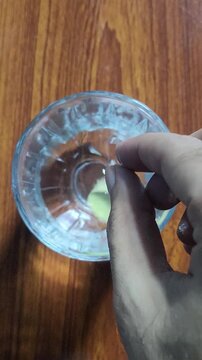 4K vertical video frame showing a yellow CAC 1000 effervescent tablet being dropped into a clear glass bowl of water, creating bubbles and fizz as it dissolves.