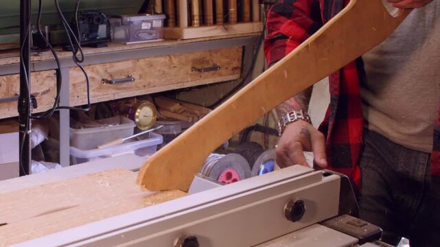 Joiner process. Workshop safety. Carpenter hand cut plank with circular table saw pushing lumber on rotating sharp blade with wooden safety handle.
