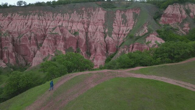Hiker exploring the stunning red ravine of Rapa Rosie in Transylvania, Romania. Geological reservation with badlands