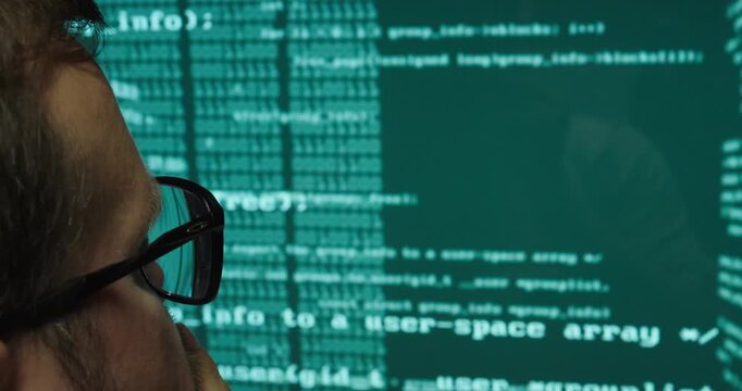 Close-up of a software developer looking at source code displayed on a computer monitor. Concept of programming, software development, information technology, coding, and digital work.