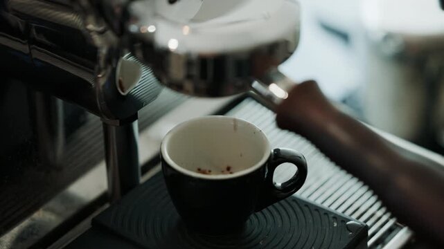 4K Pouring coffee stream from professional machine in cup. Barista man making double espresso, using filter holder. Flowing fresh ground coffee. Drinking roasted black coffee in the morning.