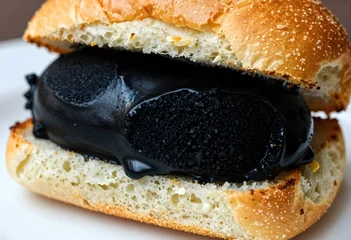Macro of jet black garlic ice cream melting inside a golden brioche bun. © stefanholm