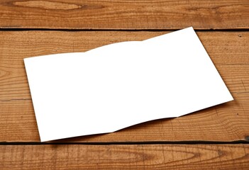 Fototapeta premium High-resolution image of a blank tri-fold brochure mockup on a textured wooden surface, communication, texture