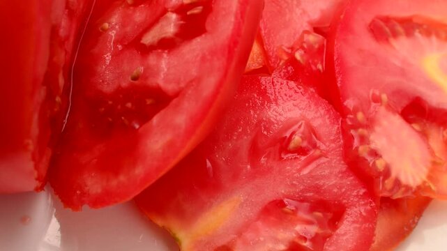 Fresh Red Tomato: Succulent slices on a white plate, ready to inspire your culinary creations. Close-up of sliced red tomatoes, an appetizing sight to awaken the taste buds.
