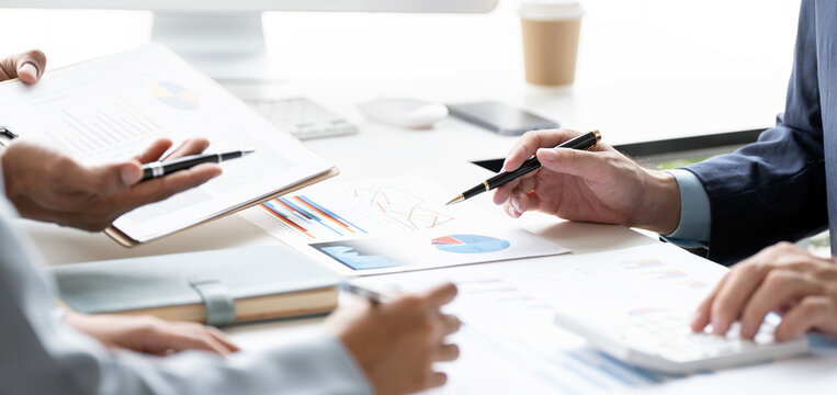 Close up of business people analyzing financial graphs and pie charts at meeting