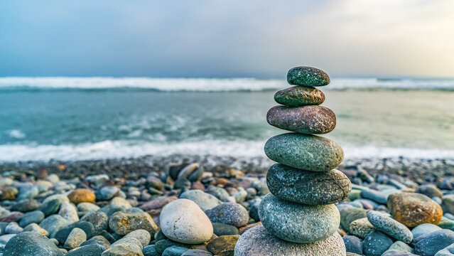 Stacked stones balanced on a pebble beach along the Pacific coast in Lima, Peru. Calm seascape with soft waves and copy space representing balance, harmony, mindfulness and stability.