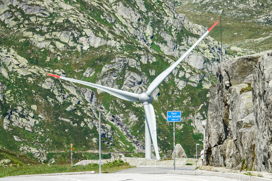 Aerial view of a wind turbine at Passo del San Gottardo with rocky mountain slopes in the background in Airolo, Ticino, Switzerland.
