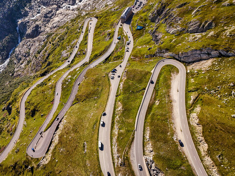 Aerial view of the winding Furka Pass road with hairpin turns, mountain slopes, and vehicles Obergoms, Valais, Switzerland.