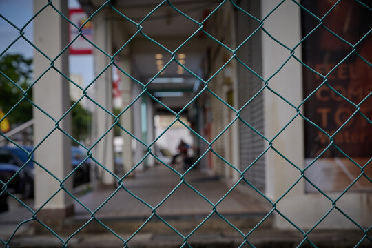 Chain Link Fence with Blurred Urban Walkway Background