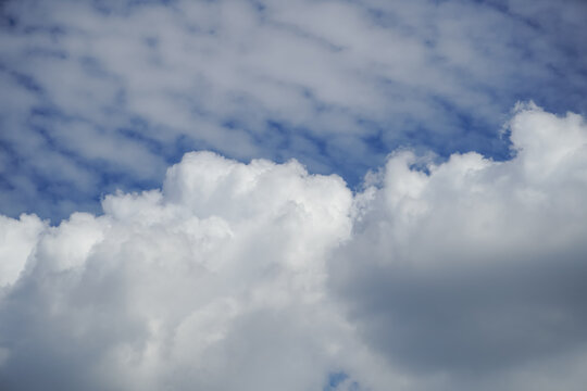 Fluffy white cumulus clouds drift across a bright blue sky on a sunny day