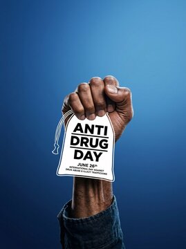 Hand holding anti drug day sign on blue background awareness campaign
