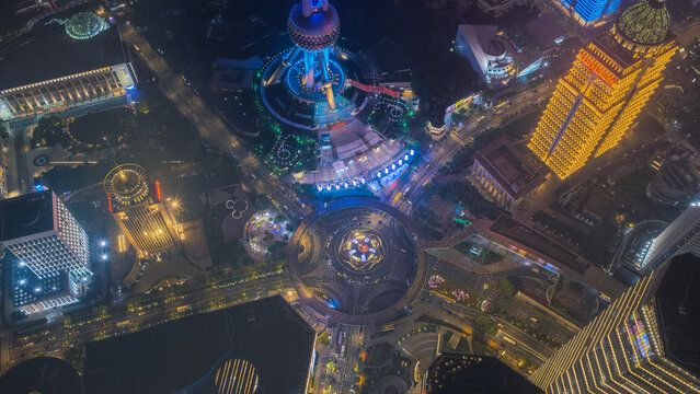 Aerial view of the illuminated Lujiazui financial district at night, featuring the Oriental Pearl Tower, glowing skyscrapers, and the circular pedestrian bridge in Shanghai, Shanghai, China.