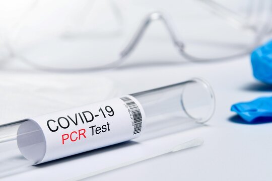 Covid-19 PCR test kit vial with medical mask protective goggles and blue nitrile gloves for healthcare website design and pandemic advertising.