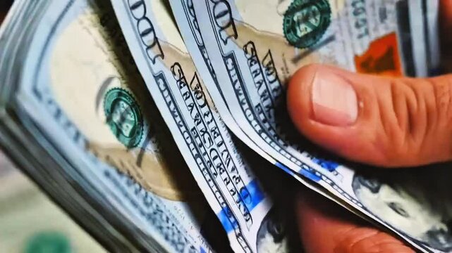Close-up of hands counting a stack of 100 US dollar banknotes quickly. Concept of cash transaction, financial management, salary payment, accounting audit, business liquidity, and wealth.
