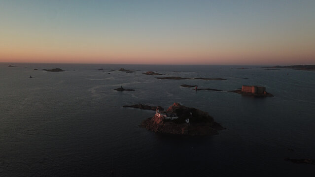 Aerial view of the lighthouse on Louet island at sunset, with the historic Chateau du Taureau in the background, in Carantec, Brittany, France.