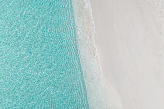 Aerial view of the clear turquoise water gently lapping against the pristine white sand beach of Vashafaru, Haa Alif Atoll, Maldives.
