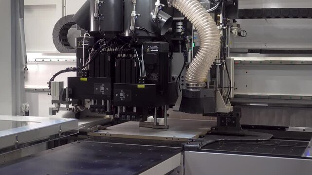 Automated CNC machining system moves multiple tool heads over a flat panel inside an industrial manufacturing machine