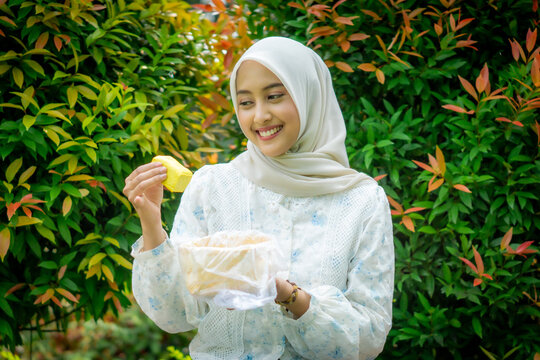 A young Asian Muslim woman enjoys tahu takwa (yellow tofu) in the garden. A typical dish from Kediri, Indonesia.