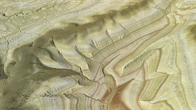 Aerial view of the arid, layered desert landscape with intricate erosion patterns and colorful soil strata in Satbayev, Ulytau Region, Kazakhstan.