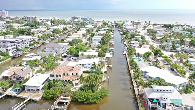 Aerial view of a canal-side residential neighborhood with houses, private docks, swimming pools, and lush tropical vegetation in Fort Myers, Florida, United States.