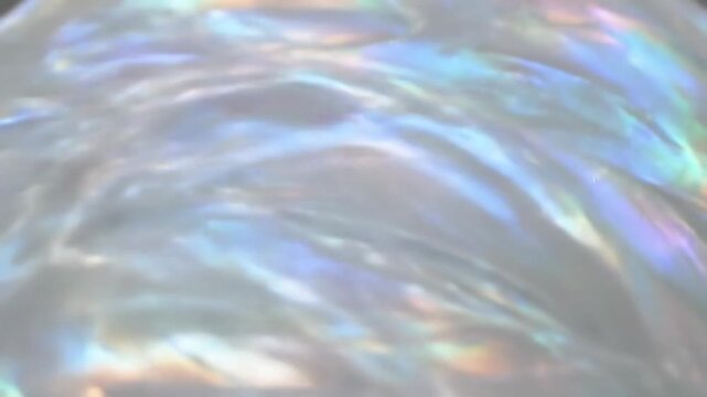 Iridescent pearlescent surface texture with fluid waves and rainbow light reflections, abstract ethereal background