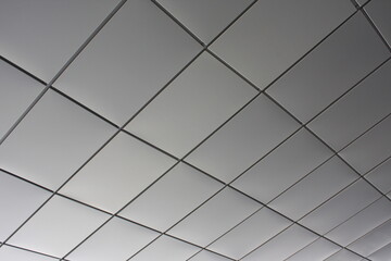 Obraz premium A modern ceiling features a geometric grid pattern with sleek white panels and dark lines.