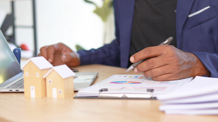 Real estate consultant analyzing property investment reports and housing market data on laptop....