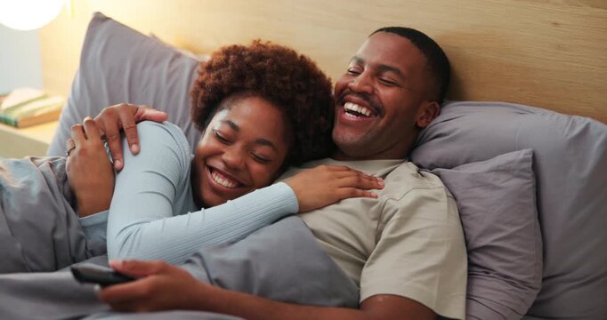 Laugh, watching tv and black couple on bed in home for comedy show, bonding or relax together. Happy, remote and man with woman in bedroom for streaming funny movie, film or series in apartment.