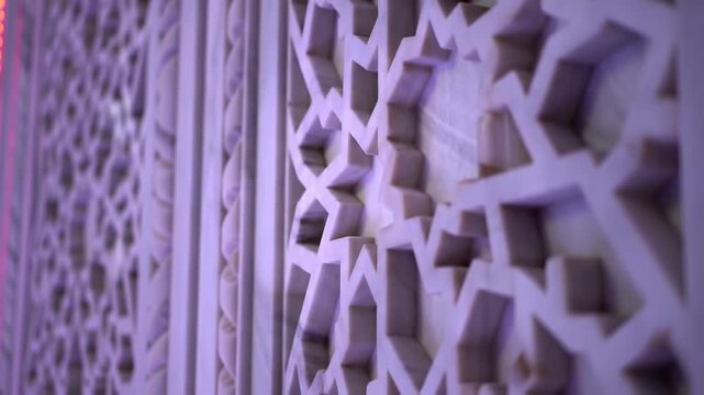 Intricate geometric Islamic patterns carved into a marble wall with soft blue light, architectural detail, arabesque design, elegant background