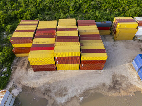 Aerial view of stacked shipping containers in the port area of Puerto Progreso, surrounded by lush tropical vegetation in Progreso, Yucatan, Mexico.