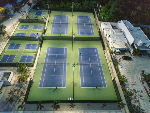 Aerial view of Provincia Golf Club featuring illuminated tennis and padel courts at night with players on the court in Merida, Yucatan, Mexico.