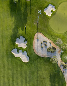 Aerial view of Provincia Golf Club featuring sand bunkers, manicured green fairways, and a tall light pole casting a long shadow in Merida, Yucatan, Mexico.