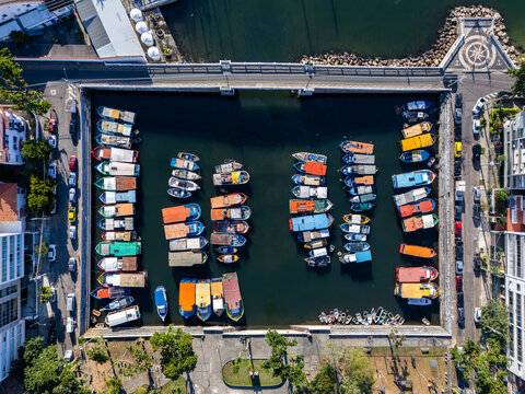 Aerial view of Quadrado da Urca marina with colorful boats moored in rows within the harbor, surrounded by urban streets and trees in Rio de Janeiro, Rio de Janeiro, Brazil.