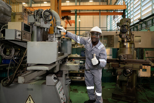 Thump up African American engineer working and control machine at auto parts factory