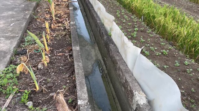 Concrete drainage ditch canal running along rural farm