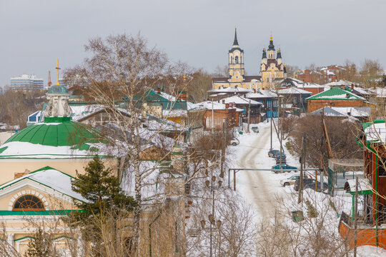 Aerial view of the historic Epiphany Cathedral surrounded by snow-covered wooden houses and bare trees in the winter cityscape of Tomsk, Tomsk Oblast, Russia.