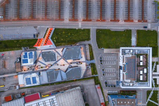 Aerial view of The Mall Luxury Outlets featuring modern geometric rooftops with solar panels, paved walkways, and surrounding parking lots in Leccio, Toscana, Italy.