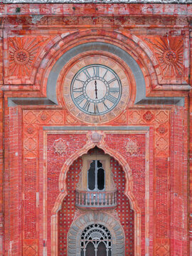 Aerial view of the ornate Moorish-style facade of Castello di Sammezzano with its intricate red brickwork, decorative carvings, and a prominent clock face in Leccio, Toscana, Italy.