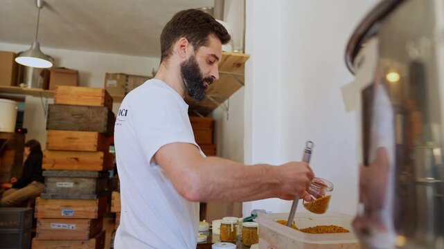 Beekeeper filling jar with natural bee pollen