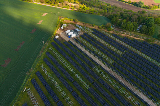 Aerial view of FVE Bohumilice solar power plant with rows of photovoltaic panels and technical containers situated amidst green agricultural fields in Klobouky u Brna, Jihomoravsky kraj, Czechia.